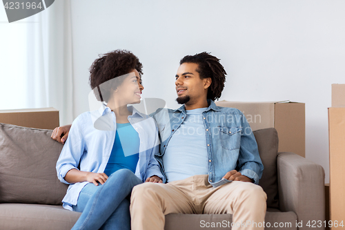 Image of happy couple sitting on sofa and talking at home