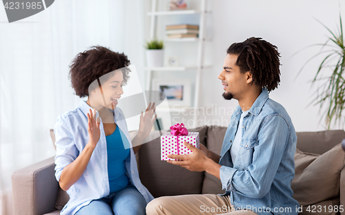 Image of happy couple with gift box at home