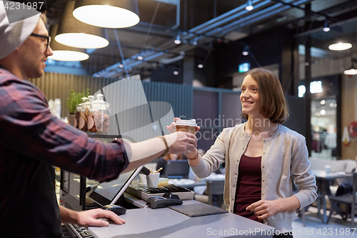 Image of seller giving coffee cup to woman customer at cafe