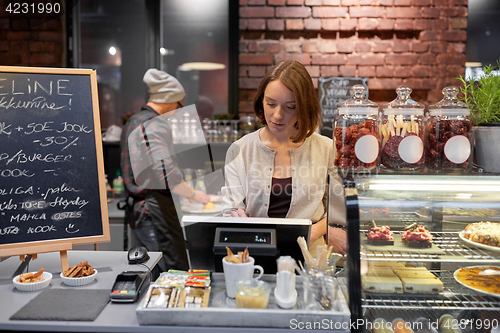 Image of woman or barmaid with cashbox at cafe