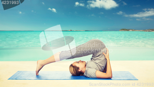 Image of woman making yoga in plow pose on mat
