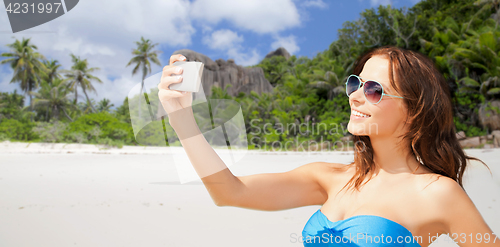 Image of woman in swimsuit taking selfie with smatphone