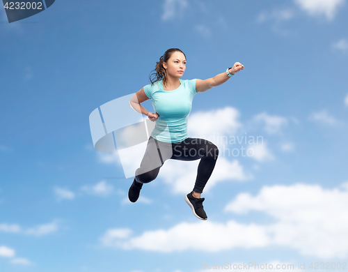 Image of happy sporty young woman jumping in fighting pose