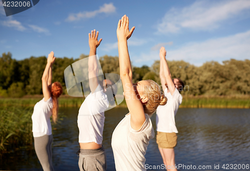 Image of group of people making yoga exercises outdoors