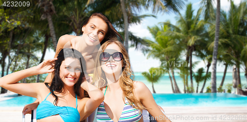 Image of happy women sunbathing in chairs on summer beach