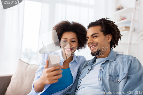 Image of happy couple with smartphones at home