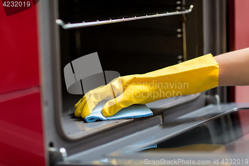 Image of hand with rag cleaning oven at home kitchen