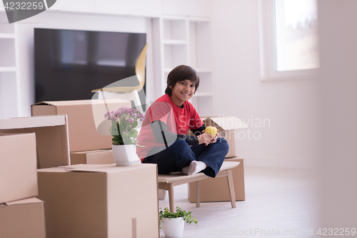 Image of boy sitting on the table with cardboard boxes around him