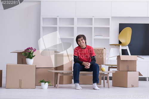 Image of boy sitting on the table with cardboard boxes around him