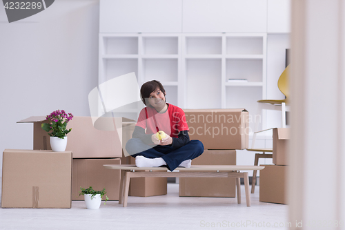 Image of boy sitting on the table with cardboard boxes around him