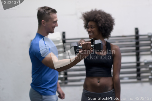 Image of black woman doing bicep curls with fitness trainer