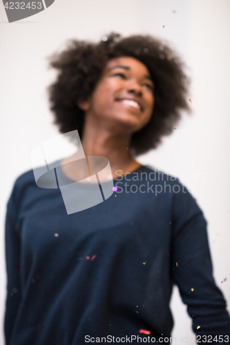 Image of African American woman blowing confetti in the air