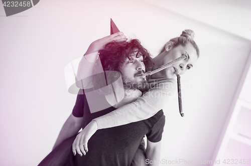 Image of couple in party hats blowing in whistle