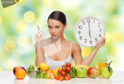 Image of woman with food and big clock sitting at table