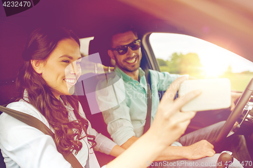 Image of happy couple in car taking selfie with smartphone