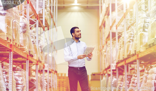 Image of happy businessman with tablet pc at warehouse