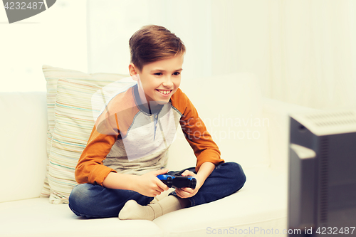 Image of happy boy with joystick playing video game at home