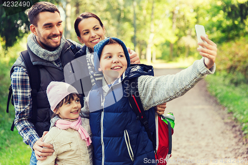 Image of family with backpacks taking selfie by smartphone