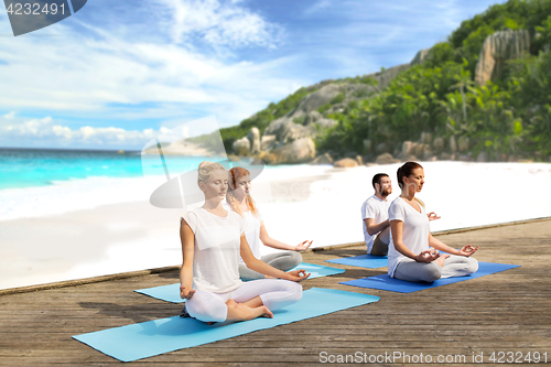 Image of people meditating in yoga lotus pose outdoors