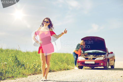 Image of women with broken car hitchhiking at countryside