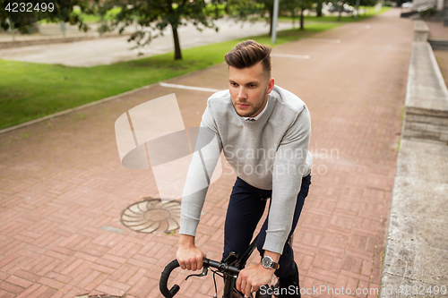 Image of young man riding bicycle on city street