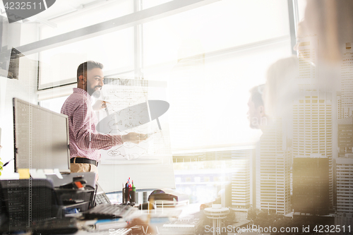 Image of business team with scheme on flipboard at office