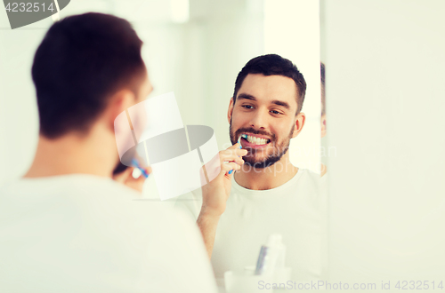 Image of man with toothbrush cleaning teeth at bathroom