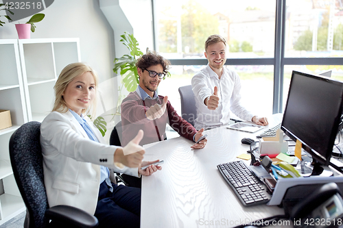 Image of business team showing thumbs up at office