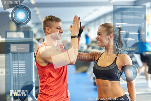 Image of smiling man and woman doing high five in gym