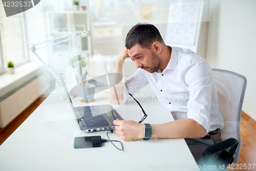 Image of stressed businessman with laptop at office