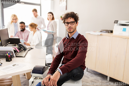 Image of happy young man over creative team in office