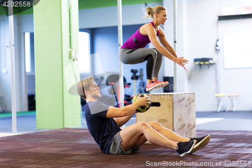 Image of woman and man with medicine ball exercising in gym