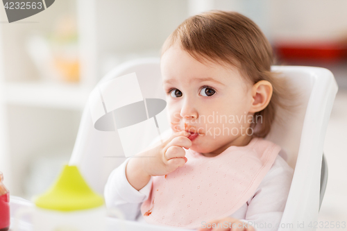 Image of happy baby girl sitting in highchair at home