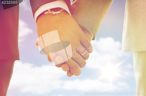 Image of close up of male gay hands with wedding rings on