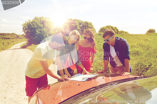 Image of happy friends with map and car at country road