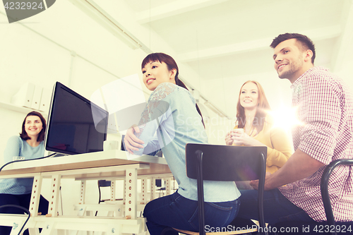 Image of happy creative team drinking coffee at office