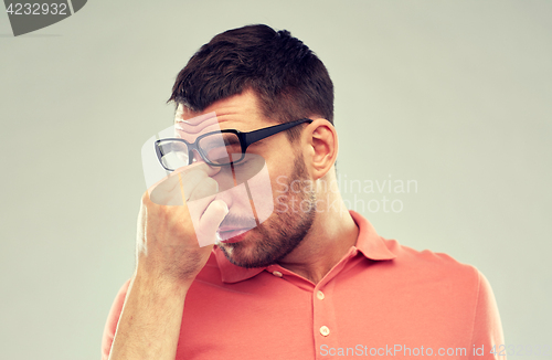 Image of tired man with eyeglasses touching nose bridge