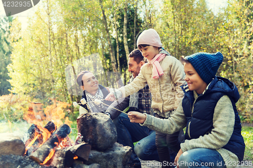 Image of happy family roasting marshmallow over campfire