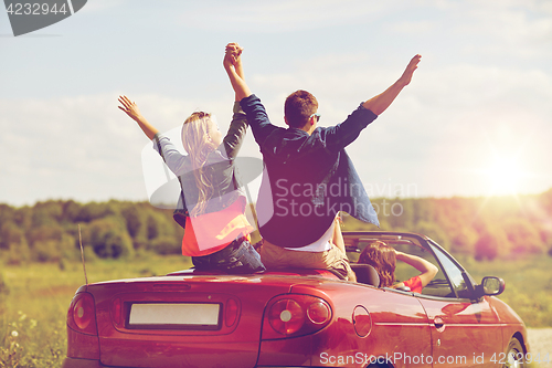 Image of happy friends driving in cabriolet car at country