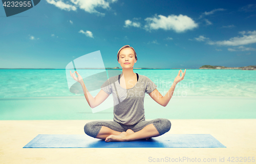Image of woman making yoga meditation in lotus pose on mat
