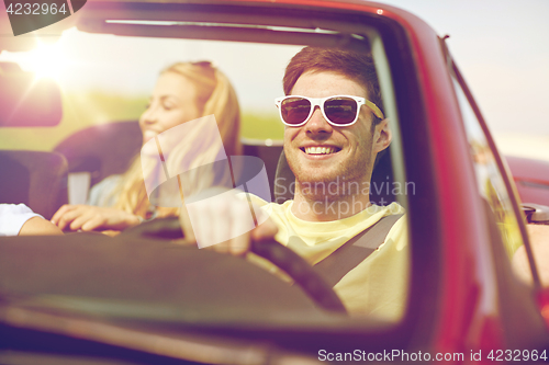 Image of happy friends driving in cabriolet car