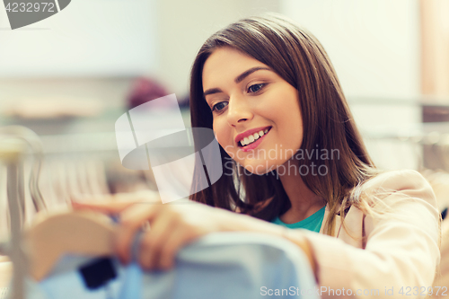 Image of happy young woman choosing clothes in mall