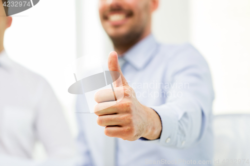 Image of hand of smiling businessman showing thumbs up