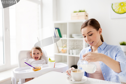 Image of happy mother and baby having breakfast at home