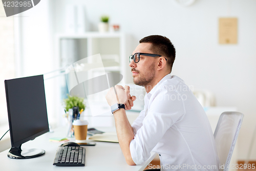 Image of businessman in glasses sitting at office computer