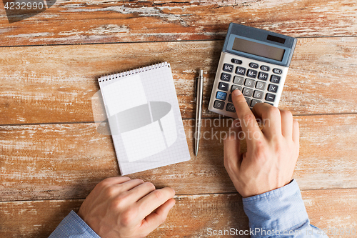 Image of close up of hands with calculator and notebook