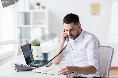 Image of businessman with pad calling on phone at office