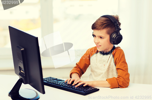 Image of happy boy with computer and headphones at home