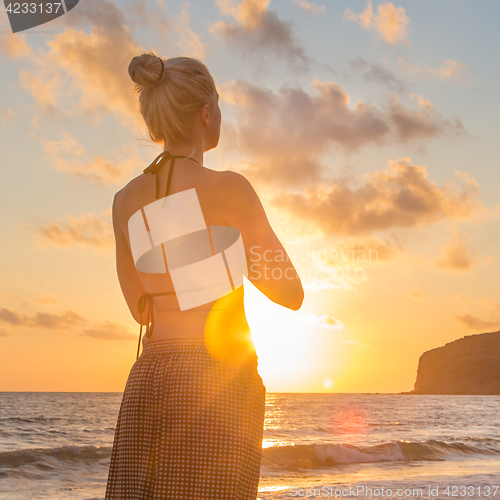Image of Woman practicing yoga on sea beach at sunset.