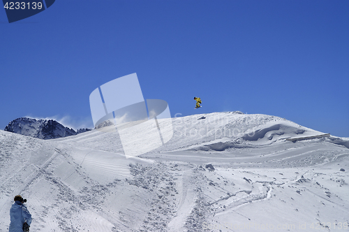 Image of Snowboarder jumping in snow park at ski resort on sun winter day